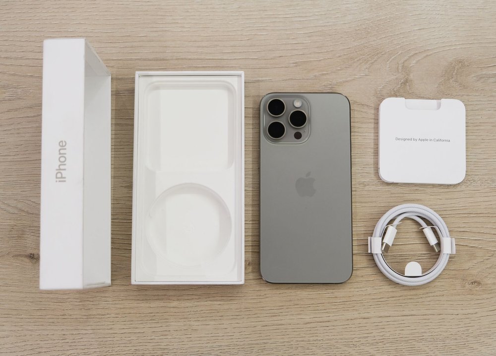 Najnowszy model iPhone'a z pudełkiem i akcesoriami na stole