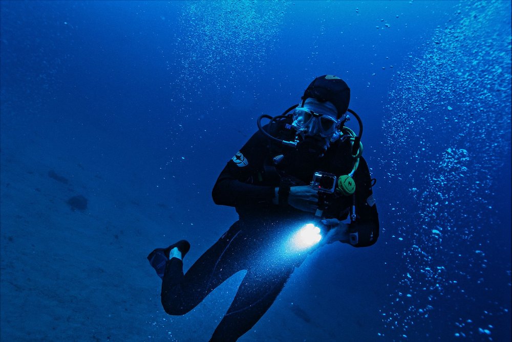 Nurek eksplorujący ocean z latarką wśród bąbelków i życia morskiego