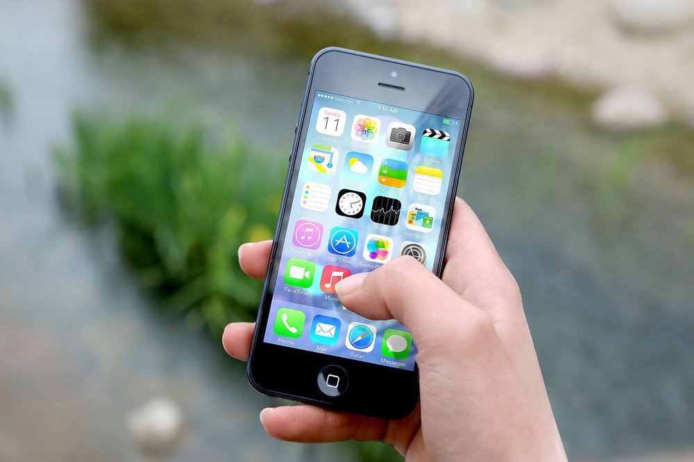 Dłoń trzymająca smartfon nad rzeką na świeżym powietrzu