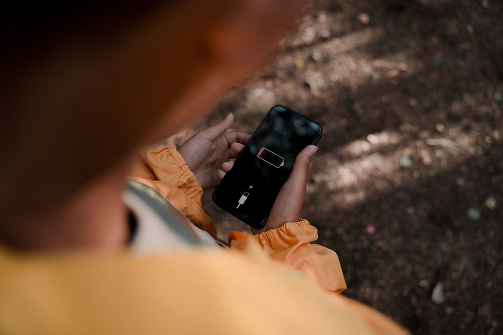 Nastolatek trzyma smartfon z niską baterią w lesie