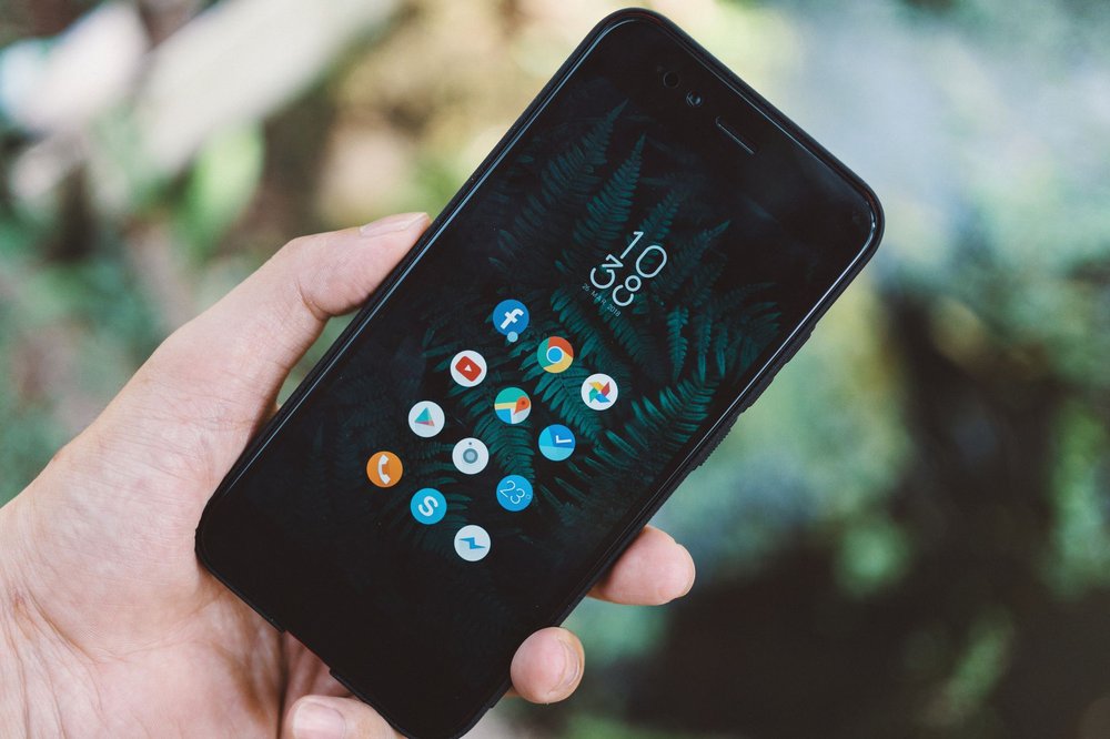Dłoń trzymająca smartfon z ikonami aplikacji