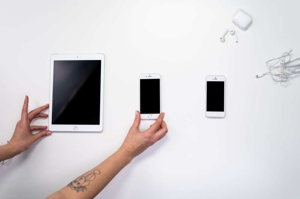 Widok z góry iPhone'a, iPad'a i słuchawek na białej powierzchni