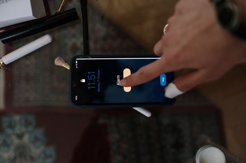 Osoba wyłączająca alarm na ekranie iPhone'a