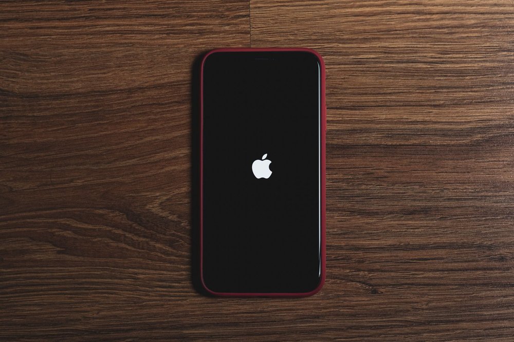 Smartfon z logiem Apple na drewnianym stole