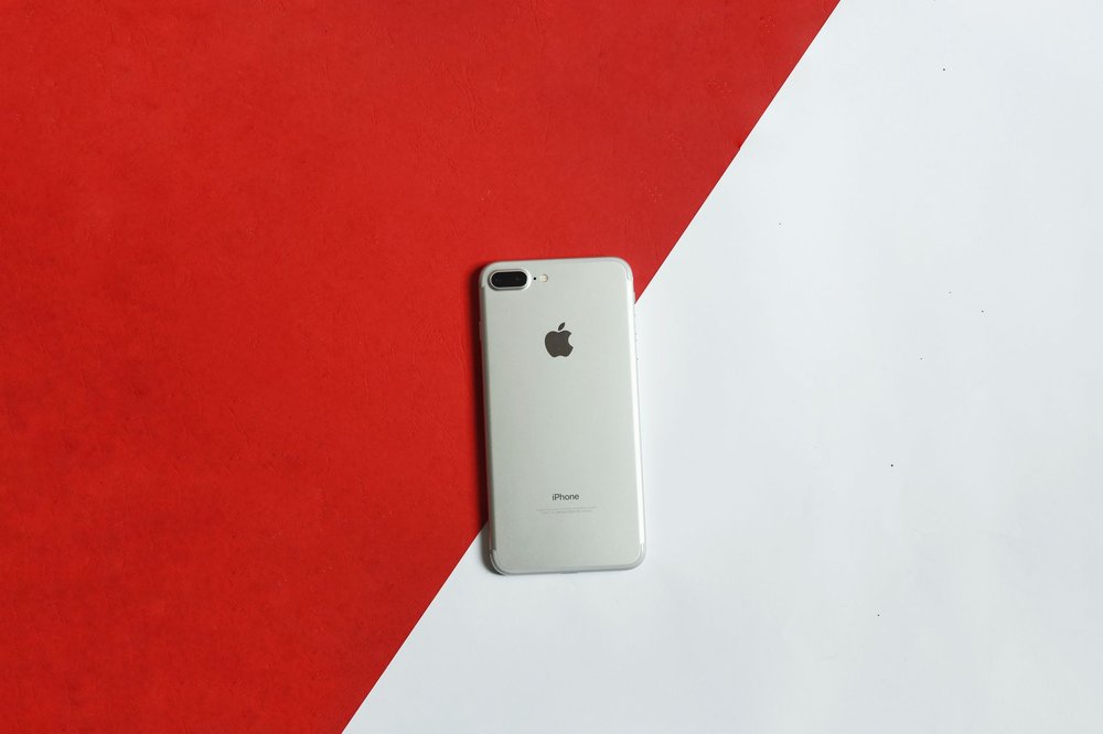 Srebrny smartfon na czerwono-białym tle, widok z góry